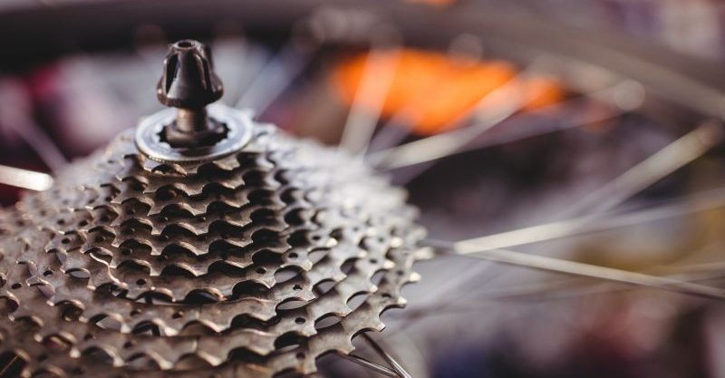 Detalhe do cassete traseiro de uma bicicleta, com engrenagens e raios da roda em destaque.