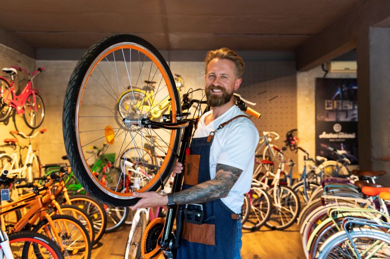 Lojista segurando uma bicicleta dentro de uma loja especializada em bikes.