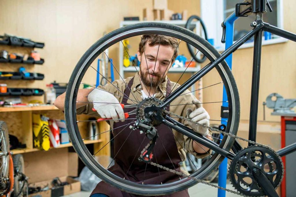 Mecânico ajustando o câmbio traseiro de uma bicicleta em uma oficina.