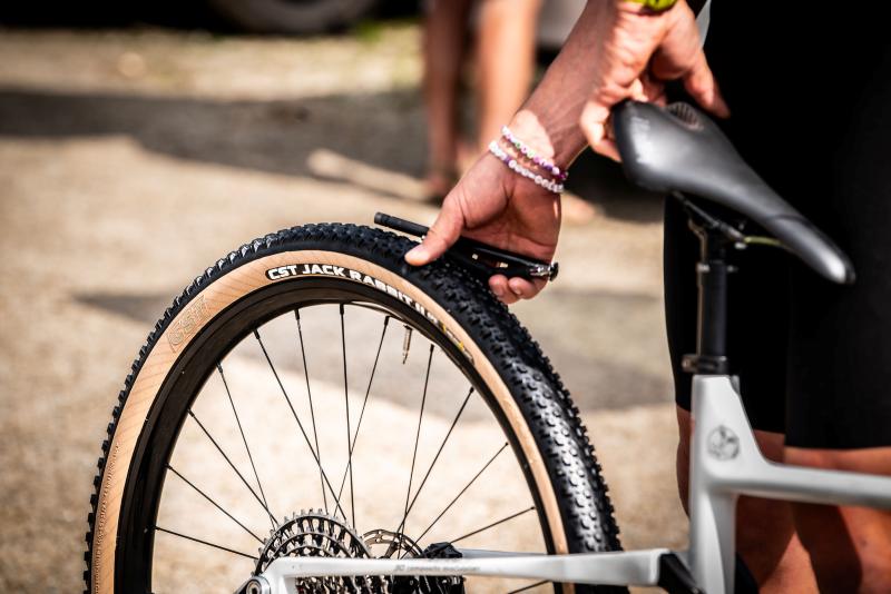 Pessoa calibrando o pneu CST Jack Rabbit em uma bicicleta, com foco no detalhe da roda.