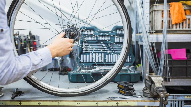 Mecânico realizando manutenção no cubo da roda de uma bicicleta em uma oficina.