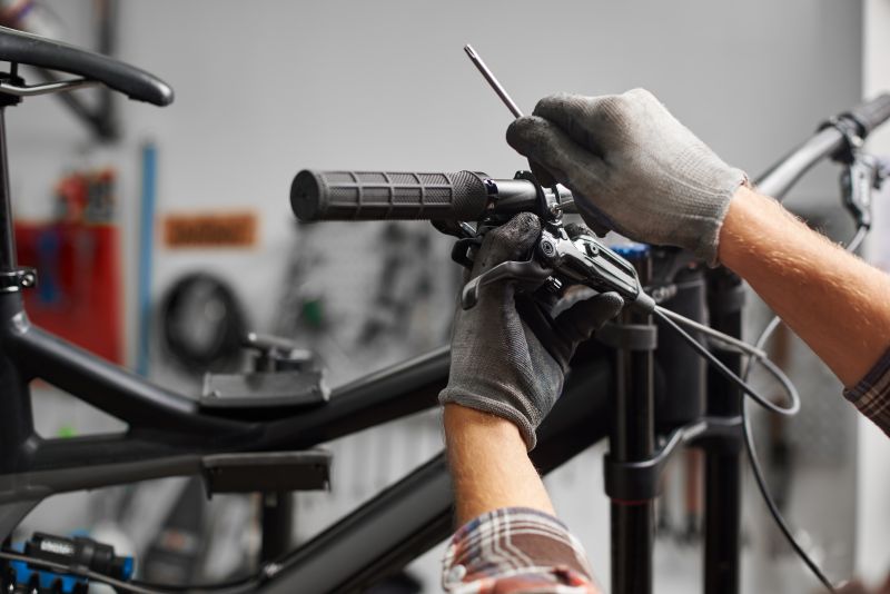 Mecânico ajustando o sistema de freio no guidão de uma bicicleta em uma oficina.