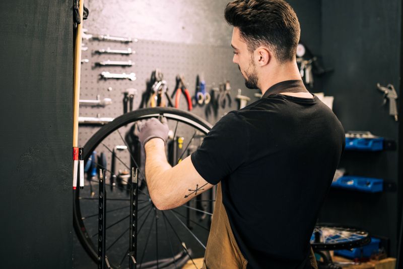 Mecânico realizando manutenção em uma roda de bicicleta dentro de uma oficina especializada.